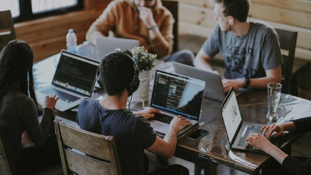 Team of colleagues collaborating around a shared table with laptops in a modern office, conveying joint review of security test environments and containment boundaries.